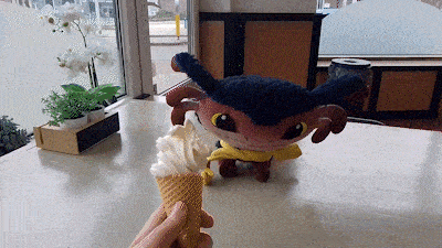 a person is holding an ice cream cone in front of a stuffed animal with horns