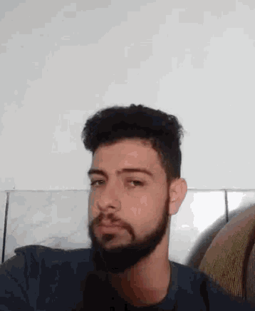 a man with a beard is sitting in a chair and making a face .