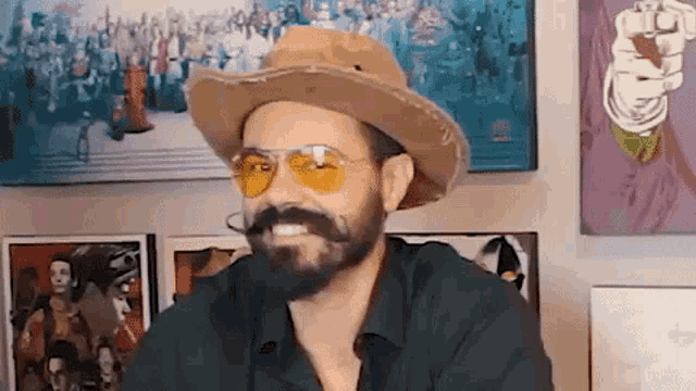 a man with a beard is wearing a cowboy hat and yellow sunglasses