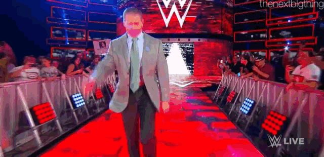 a man in a suit and tie is walking down a red carpet on a stage .
