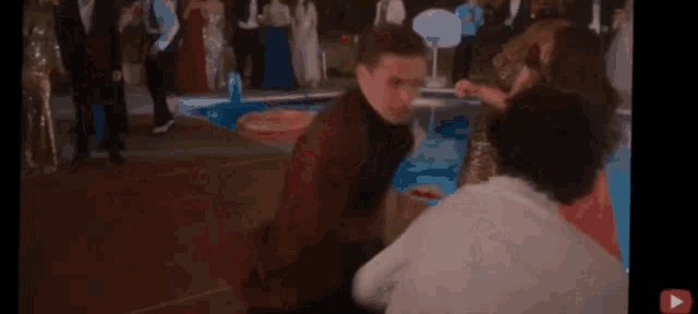 a group of people are dancing in front of a pool at a prom party .