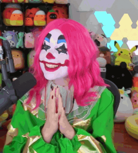 a woman with pink hair is dressed as a clown and is smiling in front of a microphone