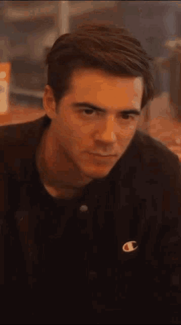 a close up of a man 's face wearing a black champion jacket .