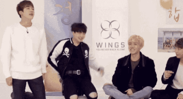 a group of young men sitting in front of a sign that says wings