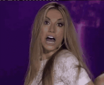 a woman with long blonde hair is making a funny face while wearing a white dress and earrings .
