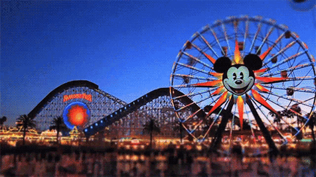 a ferris wheel with a mickey mouse face on it in front of a roller coaster