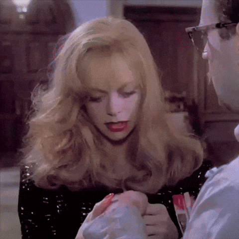 a woman with blonde hair and red lipstick is talking to a man