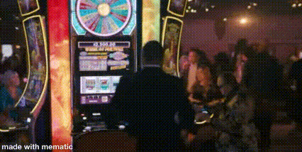 a man is playing a slot machine in a casino with a crowd of people .