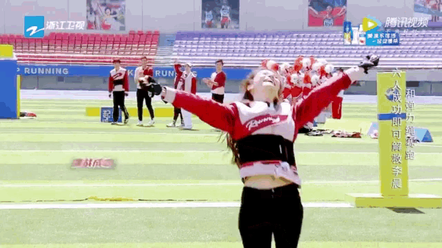 a woman is standing on a field with her arms outstretched in front of a banner that says running