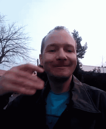 a man wearing a blue shirt and a black jacket smiles