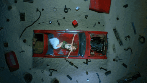 a woman is laying on the hood of a red car