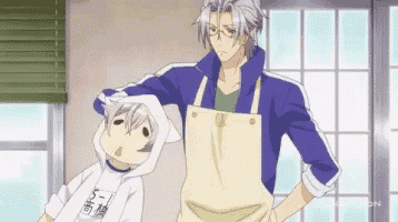 a man wearing an apron is standing next to a boy wearing a white shirt that says 5