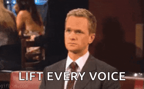 a man in a suit and tie is making a funny face while holding his finger to his mouth and saying lift every voice .
