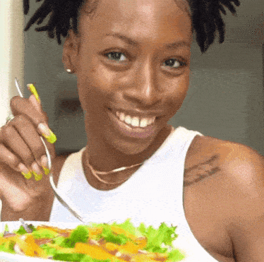 a woman with a tattoo on her shoulder is eating a salad with a fork