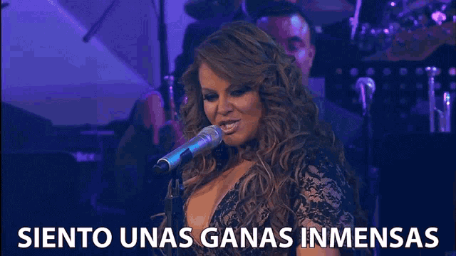 a woman singing into a microphone with the words " siento unas ganas inmensas " above her