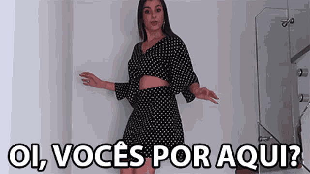 a woman in a black and white polka dot dress is standing in a room with the words ol voce por aqui written above her