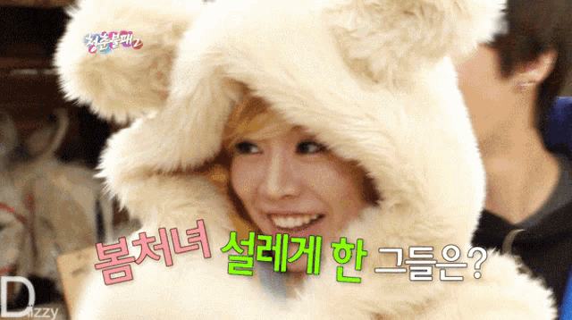 a woman wearing a furry hat with korean writing on it is smiling