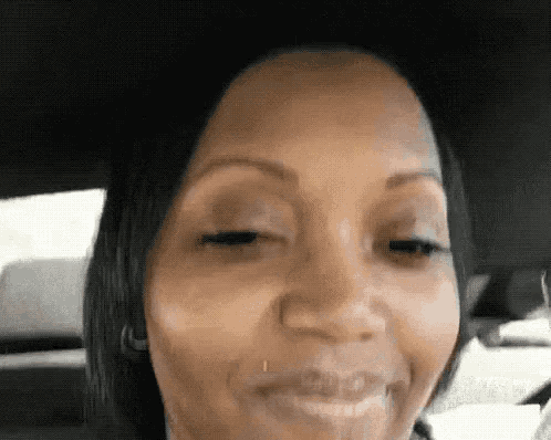 a close up of a woman 's face in a car with her eyes closed and her mouth open .
