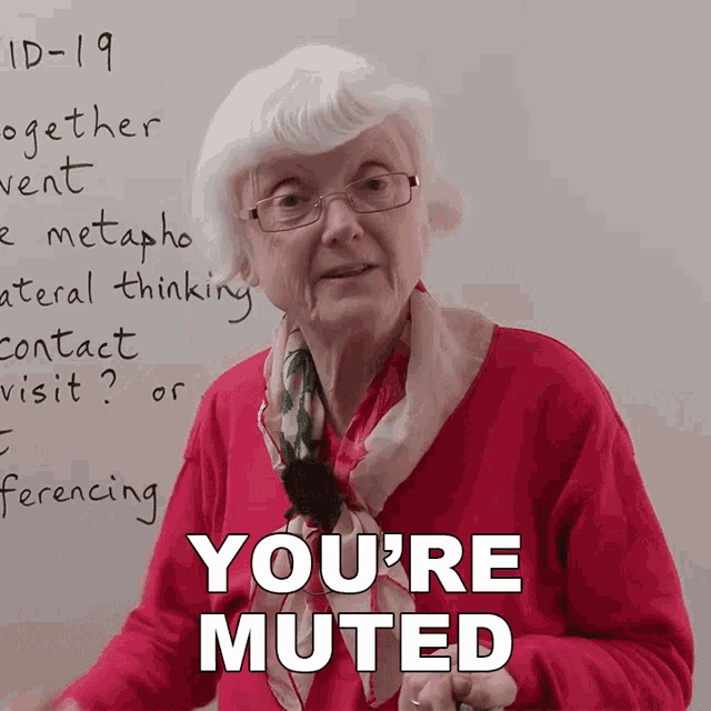 an elderly woman stands in front of a whiteboard with the words " you 're muted " on it
