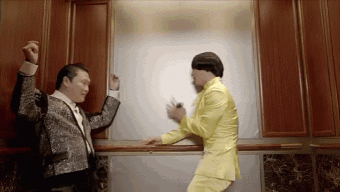 two men in suits are dancing in an elevator and one is wearing a yellow suit