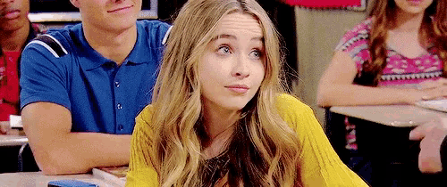 a girl in a yellow sweater is sitting in a classroom with other students .