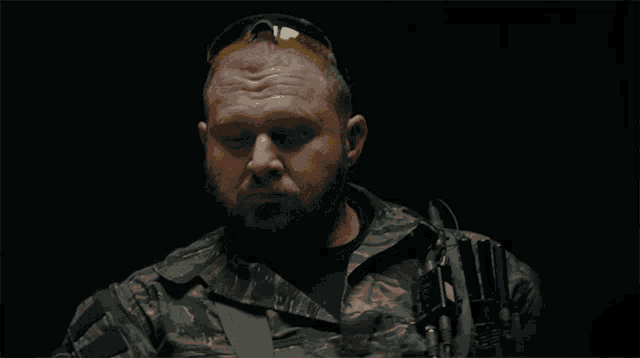 a man with a beard wearing sunglasses and a camouflage uniform