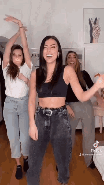 three women are standing next to each other and dancing .