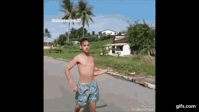 a shirtless man in blue shorts is walking down the street .