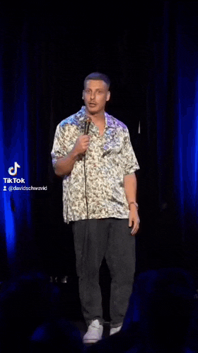 a man is standing in front of a microphone on a stage .