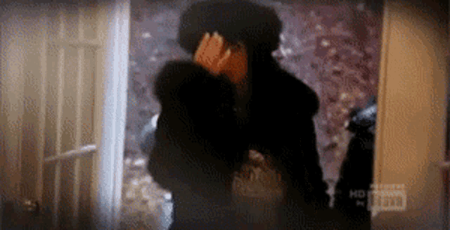 a man in a fur coat is standing in a doorway covering his face .