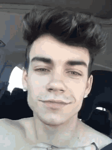 a young man without a shirt is sitting in the back seat of a car .
