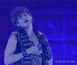 a man without a shirt is singing into a microphone while dancing on a stage .