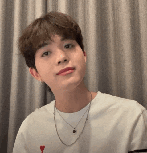a young man wearing a white shirt and a silver necklace