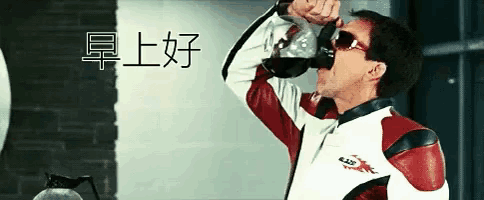 a man wearing sunglasses is drinking from a bottle with chinese writing behind him