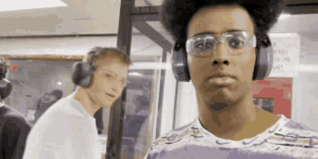 a man wearing headphones and glasses stands in front of a sign that says fire alarm