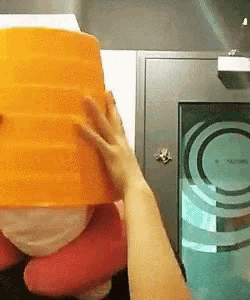 a person is holding a large orange bucket over their head