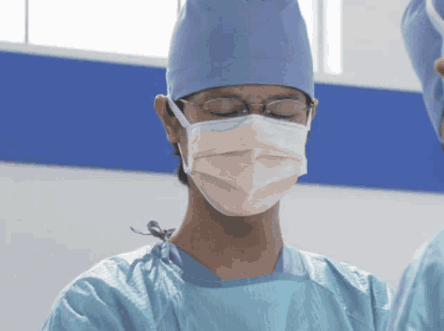 a surgeon with his eyes closed wearing a mask and gown