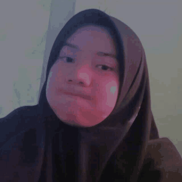a close up of a woman wearing a hijab making a funny face .