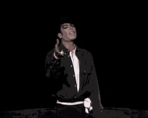 a man wearing a cowboy hat and a black jacket is standing in the dark .