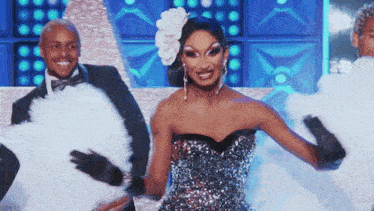 a woman in a silver dress is dancing with two men in tuxedos