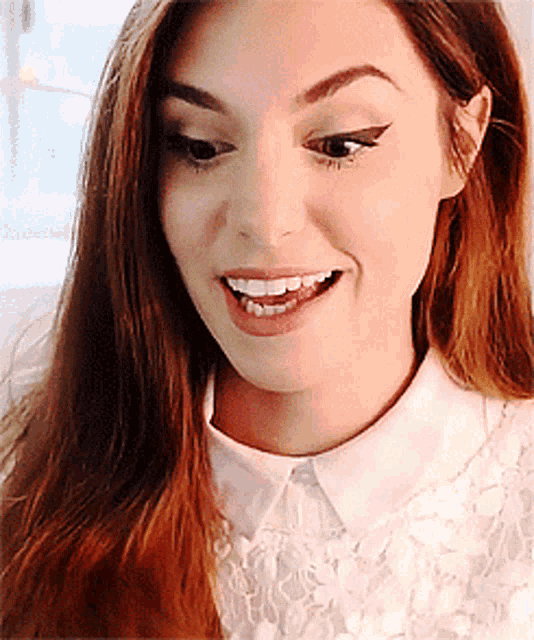 a close up of a woman 's face wearing a white shirt with a pink collar