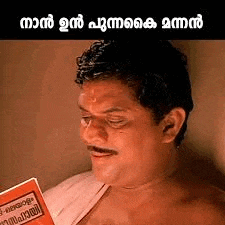 a man with a mustache is reading a book in malayalam .