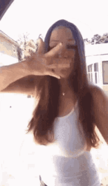 a woman is covering her face with her hand .