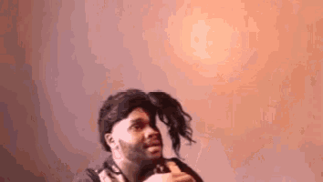 a man wearing a wig is holding a doll in his hand .