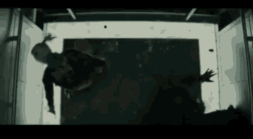 a person is falling through a door in a dark room in a movie .