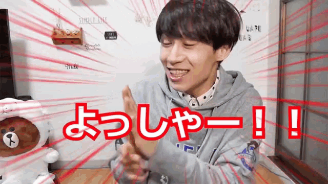 a man in a gray hoodie is smiling with red letters that say !!