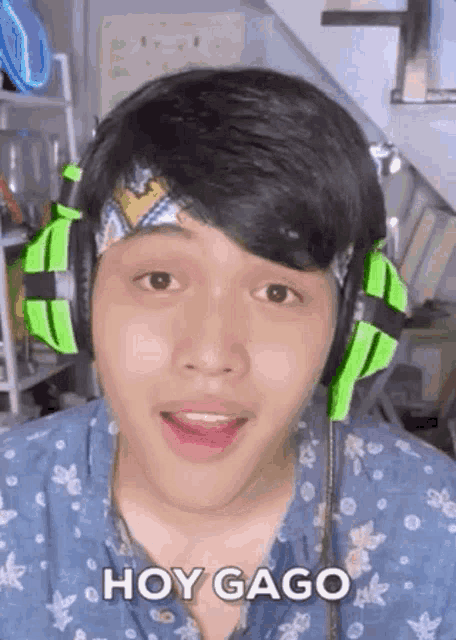 a young man wearing green headphones and a headband is making a funny face .