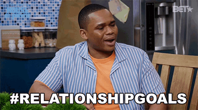 a man in a striped shirt is sitting in a wooden chair and says relationshipgoals