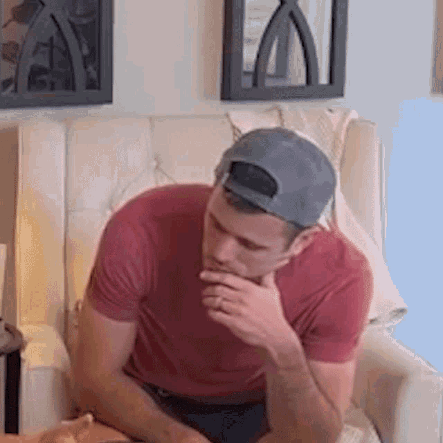 a man wearing a baseball cap is sitting in a chair