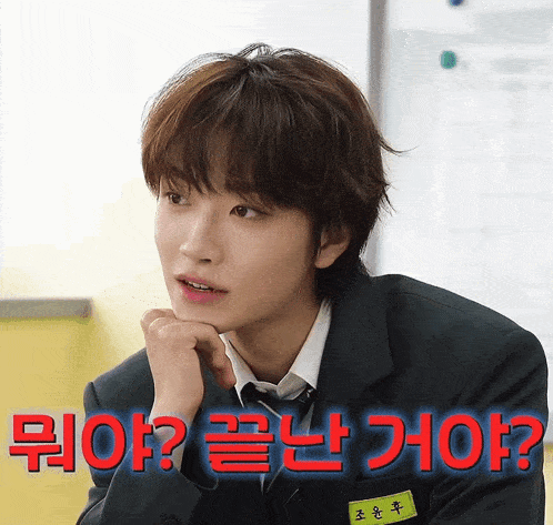 a man in a suit and tie is sitting in front of a sign that says ' ? ' on it